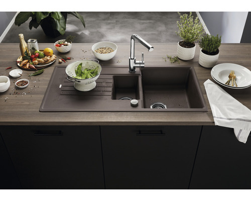 Spüle aus Verbundwerkstoff mit Abtropffläche und Einhebelmischer auf einer Küchentheke.