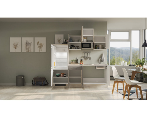 Kompakte Küche mit Kühlschrank, Spüle, Mikrowelle und Stauraum in einem hellen Raum