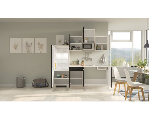 Kompakte Küchenzeile mit Spüle, Kühlschrank, Hängeschränken und Esstisch in einem hellen Raum