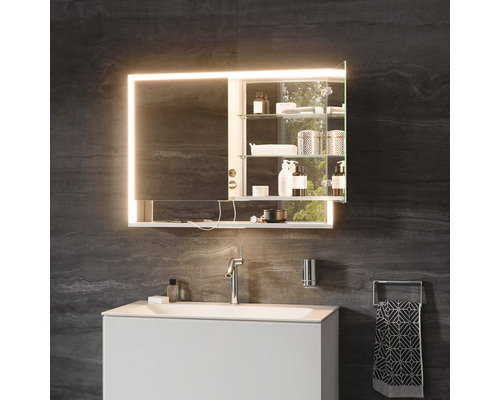 Badezimmer mit beleuchtetem Spiegelschrank, Waschtisch und Armatur vor dunkler Wand