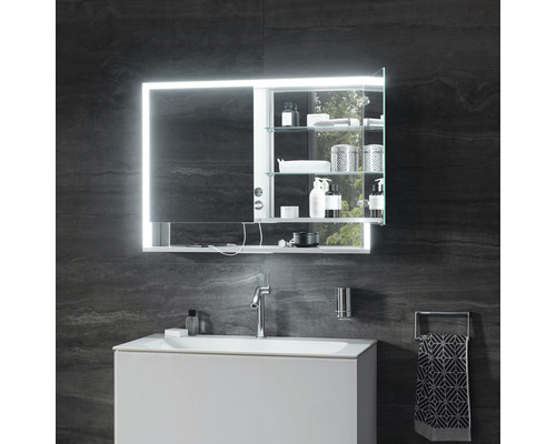 Badezimmer mit Waschbeckenunterschrank, Armatur, Handtuchhalter und beleuchtetem Spiegelschrank