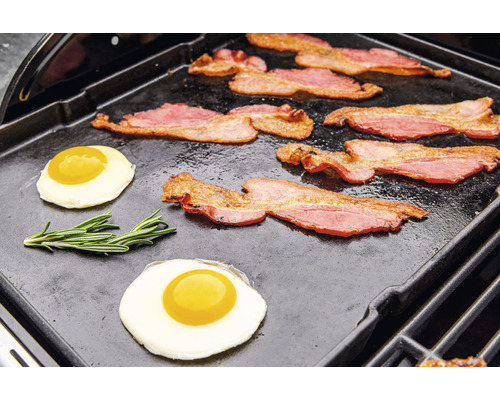 Speck und Spiegeleier werden auf einer Grillplatte zubereitet.