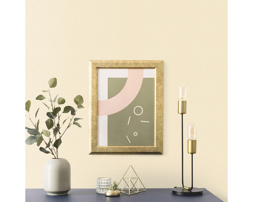 Dekoratives Arrangement mit einem gerahmten Bild, einer Vase mit Eukalyptus, einem Windlicht, einer Dekoration und einer Tischlampe auf einem Tisch