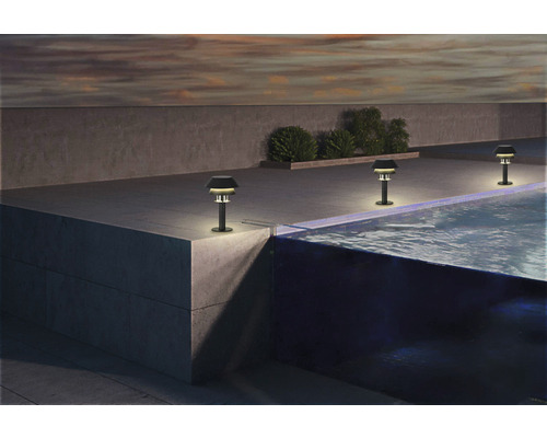 Drei Gartenleuchten aus Metall stehen neben einem Swimmingpool.