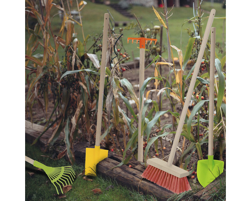 Gartenwerkzeuge wie Rechen, Besen und Schaufeln im Beet