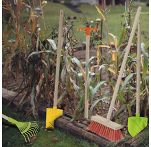 Gartenwerkzeuge wie Rechen, Schaufel und Besen im Gartenbeet