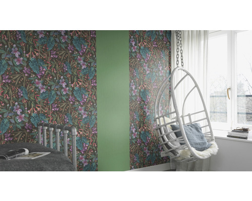 Dekoriertes Zimmer mit Tapete mit Blumenmuster, einem Schaukelstuhl und einem Bett.