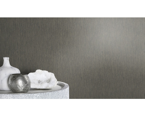 Nahaufnahme einer strukturierten Wandtapete neben dekorativen Objekten auf einem Tisch.