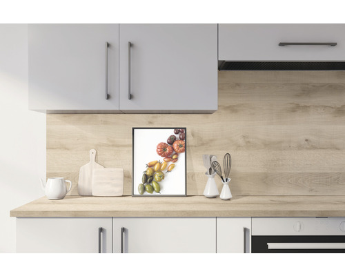Helle Küche mit Küchenschränken, Arbeitsplatte aus Holzdekor, Schneidebrettern, Teekanne und einem gerahmten Bild von verschiedenen Tomaten
