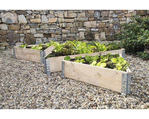 Drei hölzerne Hochbeete mit Metallbeschlägen im Garten.