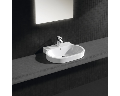 Waschbecken mit Armatur auf einer Ablage vor einer dunklen Wand mit Spiegel