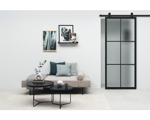 Wohnzimmer mit Sofa, Couchtischen, Wanddekoration und Glasschiebetür
