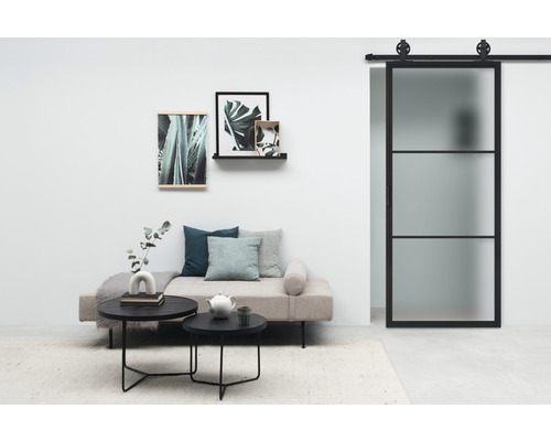 Helles Wohnzimmer mit Sofa, Couchtisch, Pflanzenbildern und Schiebetür