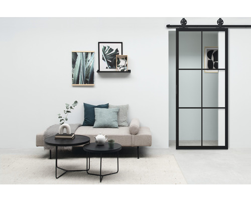 Wohnzimmer mit Sofa, Couchtisch, Bildern an der Wand und Schiebetür