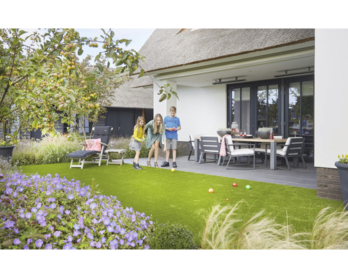 Familie spielt Boule im Garten mit Kunstrasen, Gartenmöbeln und Pflanzen