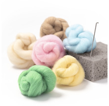 Verschiedenfarbige Wollfasern mit Filznadel und Unterlage