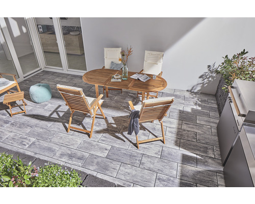 Terrasse mit Gartenmöbeln aus Holz und Pflastersteinen