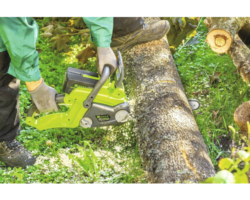 Eine Person sägt mit einer Akku-Kettensäge einen Baumstamm.