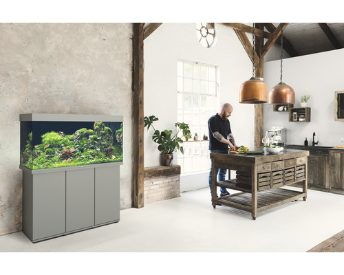 Heller Raum mit Aquarium auf Schrank und Person beim Kochen