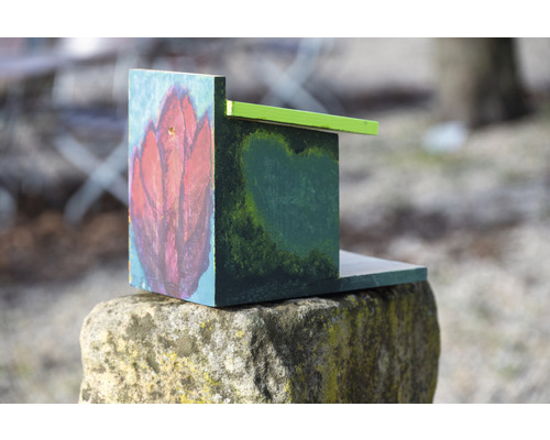 Bemaltes Vogelhaus aus Holz auf einem Stein