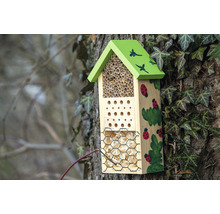 Insektenhotel mit Füllmaterial und dekorativen Malereien am Baum
