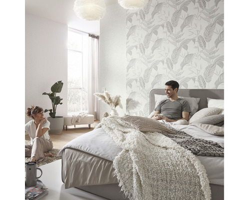 Helles Schlafzimmer mit floral gemusterter Tapete, Bett und entspanntem Paar