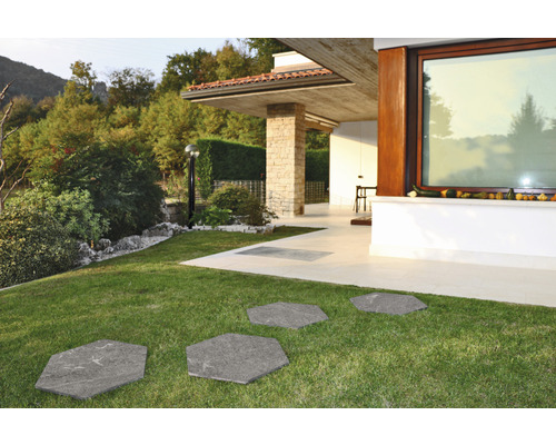 Gartenweg aus sechseckigen Steinplatten im Rasen vor einem modernen Haus.