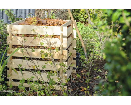 Komposter aus Holzlatten im Garten mit Laub gefüllt