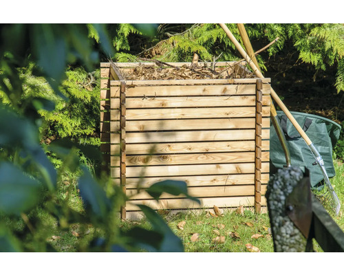 Holzkomposter im Garten mit Gartengeräten