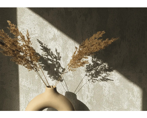 Dekorative Trockenblumen in einer Keramikvase vor einer Wand mit Schattenwurf