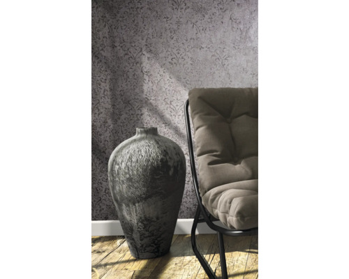 Dekorative Vase neben einem Stuhl vor gemusterter Tapete