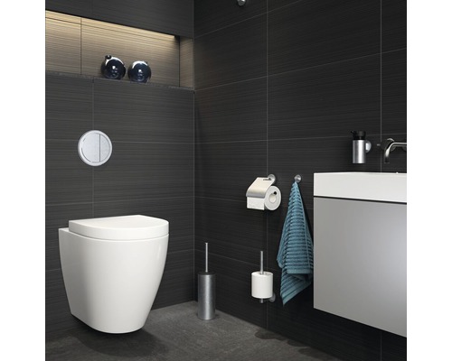 Modernes Badezimmer mit wandhängendem WC, Waschtisch und dunklen Fliesen.