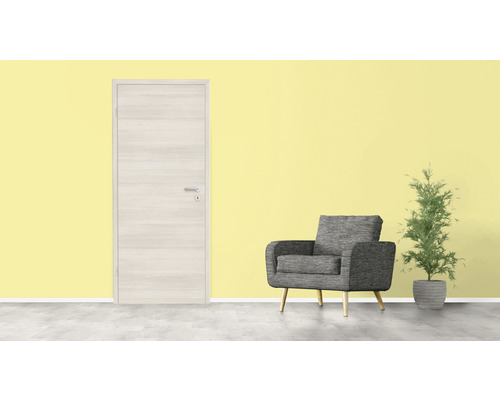 Zimmertür aus Holz, grauer Sessel und Zimmerpflanze vor gelber Wand