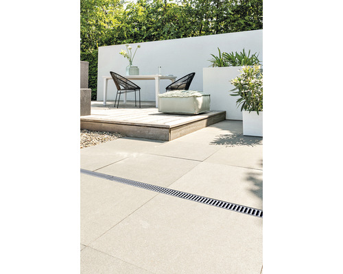 Terrassenszene mit Entwässerungsrinne, Tisch, Stühlen, Pflanzen und Sitzhocker