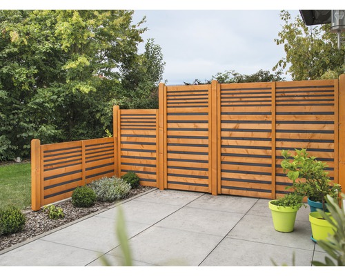 Gartenszene mit Holzzaun mit horizontalen Latten auf einer Terrasse.