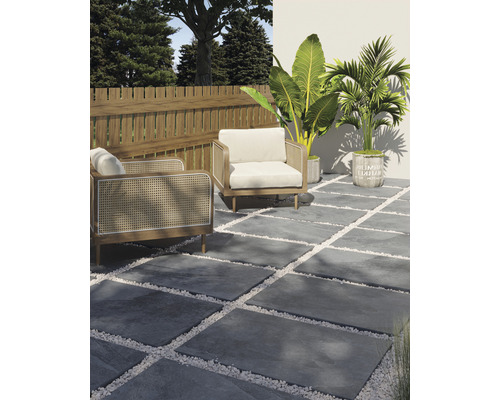 Terrassengestaltung mit grauen Steinplatten, weißen Zierkieseln, zwei Sesseln, Holzzaun und Pflanzen