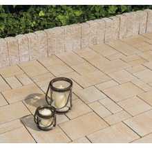Gepflasterte Terrasse mit Kerzenlaternen und Begrenzungsmauer