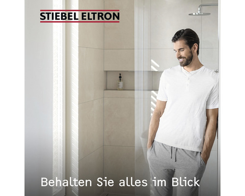 Mann steht in modernem Badezimmer mit Dusche und Stiebel Eltron Logo