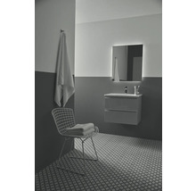 Modernes Badezimmer mit Waschtisch, beleuchtetem Spiegel, Handtuch und dekorativen Fliesen