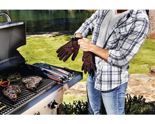 Mann zieht Grillhandschuhe vor Grill an