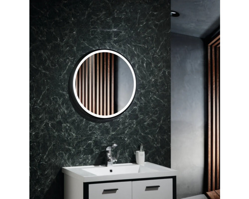 Badezimmer mit rundem Spiegel, Waschbecken und Armatur vor einer gemusterten Wand