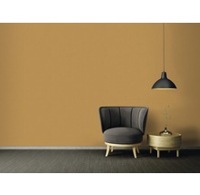 Wohnzimmer mit Sessel, Beistelltisch und Hängelampe vor einer einfarbigen Wand