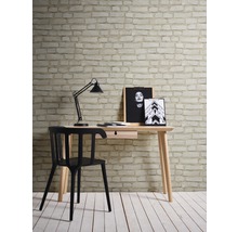 Arbeitszimmer mit Schreibtisch, Schreibtischlampe und Stuhl vor einer Wand mit Backsteintapete