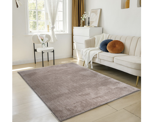 Heller Raum mit Teppich, Sofa, Stuhl und Kommode.