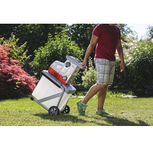 Mann transportiert Häcksler mit Auffangbehälter im Garten.