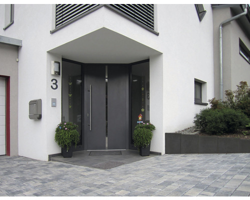 Eingangsbereich eines Hauses mit grauer Haustür, Hausnummer und Pflanzenkübeln