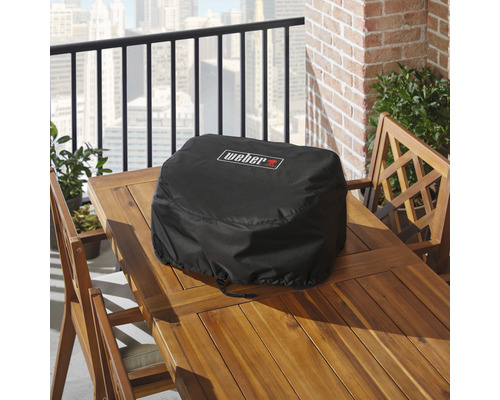 Schwarze Weber Grill Abdeckhaube auf einem Holztisch