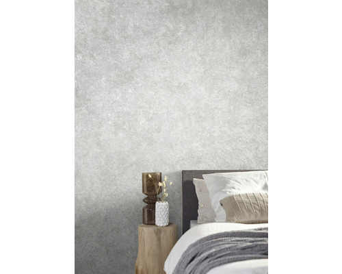 Helles Schlafzimmer mit Bett, Nachttisch und Zierobjekten vor einer grauen Wand