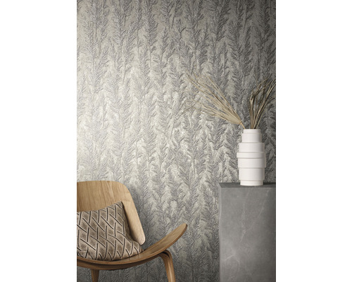 Raumansicht mit strukturierter Tapete mit Pflanzenmuster, einem Holzsessel und einer weißen Vase.