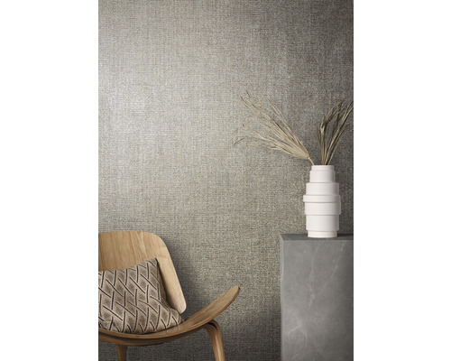 Nahaufnahme einer Wand mit Textiltapete, einem Holzsessel und einer Dekoration in einer Vase